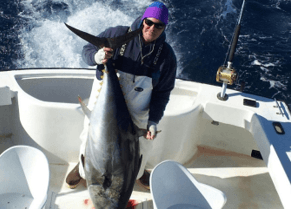 Charter angler holding up a huge Bluefin Tuna by the tail.