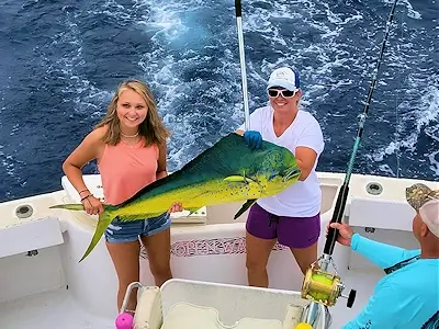 Young lady angler with lady mate holding up nice colorful mahi.